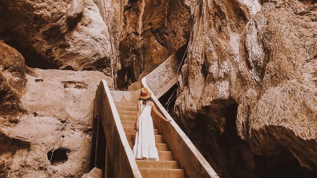 sunlight rays entering a limestone cave creating bright reflections on the rock walls
