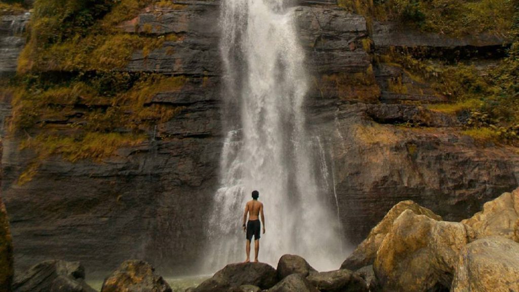 Visitor standing near the base of Cunca Lega Waterfall Tengku Lese in Flores Indonesia