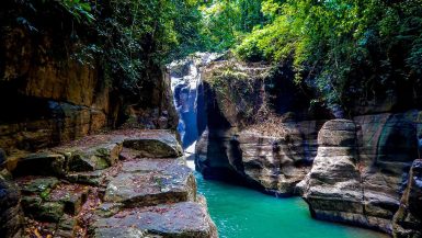 Cunca Wulang Waterfall canyon with turquoise river and rock cliffs in Flores Indonesia