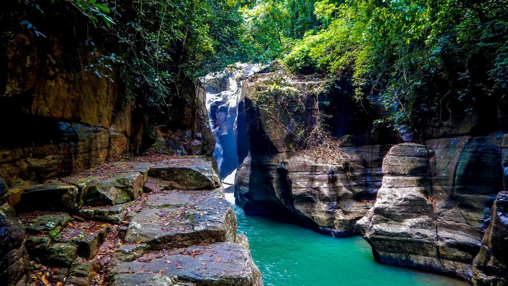 cunca wulang waterfall flowing between rocky canyon walls