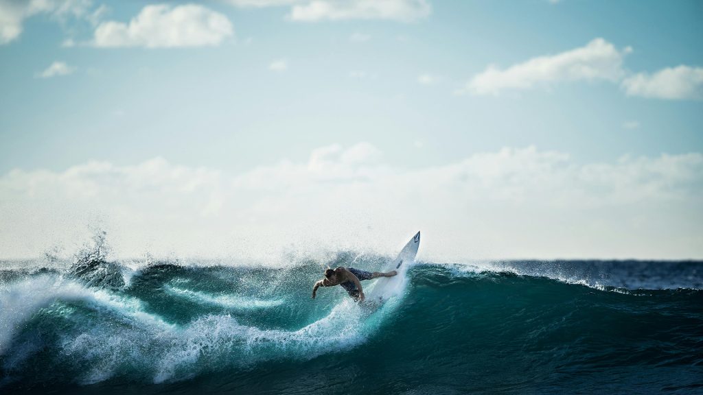 surfer carving through waves at kalala beach