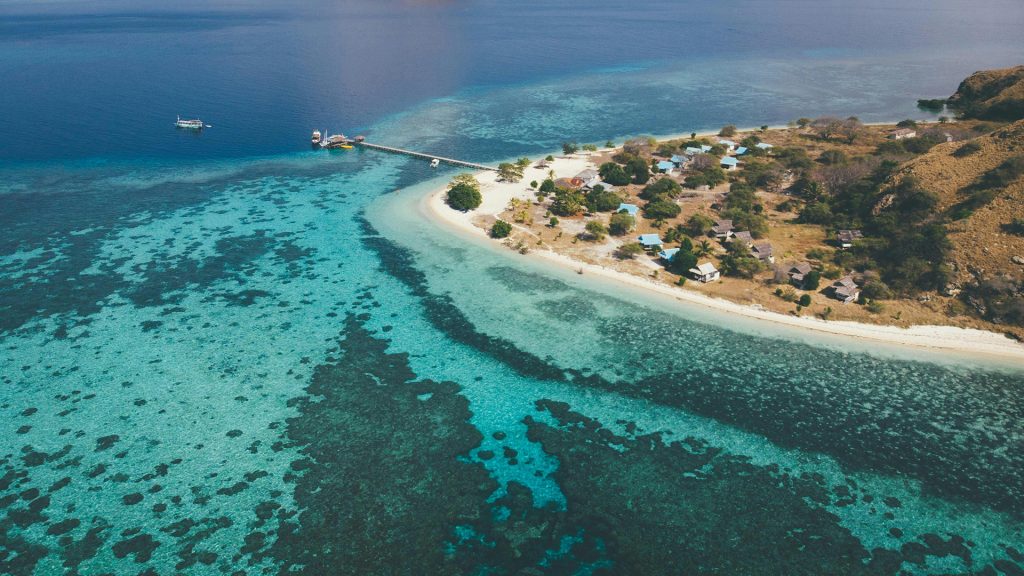 Beachfront bungalows on Kanawa Island with coral reef shoreline and clear water in Flores Indonesia