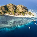 Kanawa Island Flores aerial view with coral reef, white sand beach, and boats near Labuan Bajo