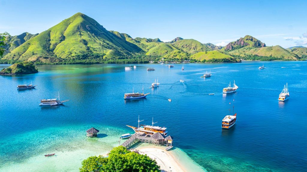 Kelor Island in Komodo National Park surrounded by green hills and boats in Labuan Bajo Flores