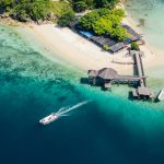 Kelor Island Labuan Bajo aerial view with wooden pier, white sand beach, and clear turquoise water
