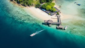 Kelor Island Labuan Bajo aerial view with wooden pier, white sand beach, and clear turquoise water