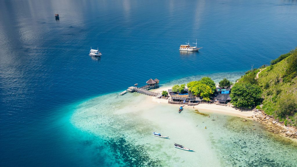 Boats sailing in Labuan Bajo sea toward Kelor Island during island hopping tour in Komodo National Park