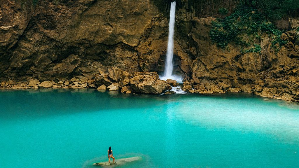 matayangu waterfall flowing into turquoise pool inside rocky canyon