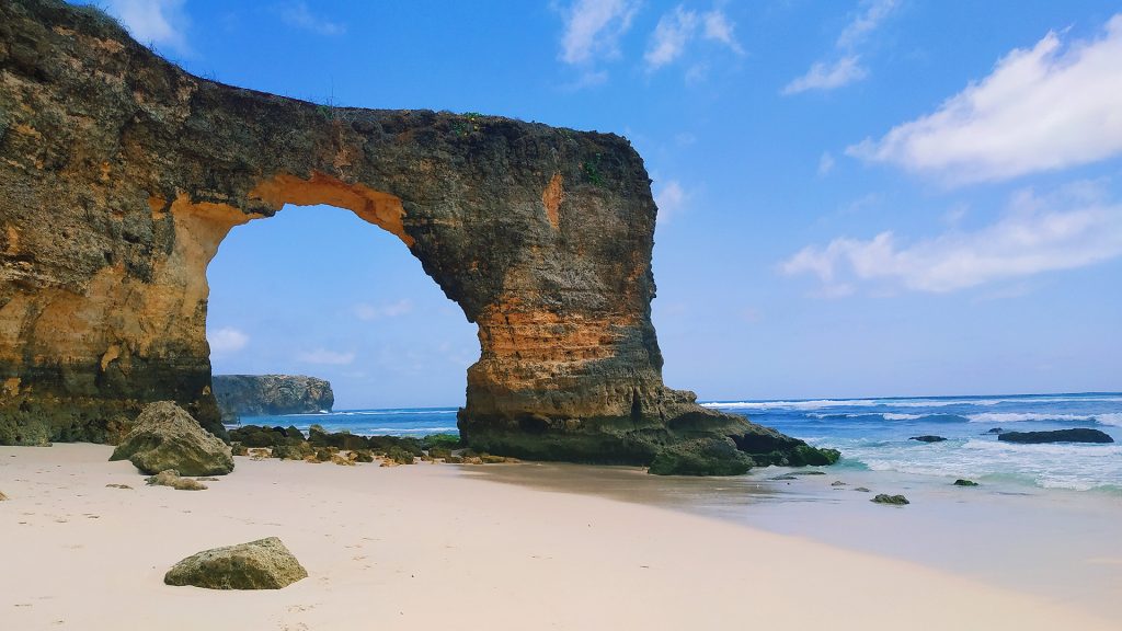 massive rock arch formation on the coastline at mbawana beach sumba island