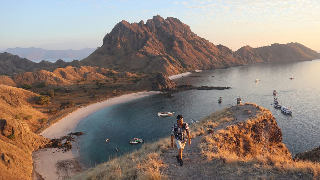 hiker walking along padar island ridge overlooking bays in labuan bajo