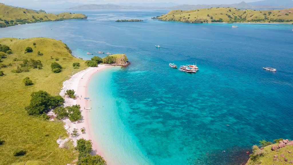 pink sand beach surrounded by clear tropical water in komodo national park