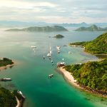Waecicu Beach Labuan Bajo aerial view with turquoise water, boats, and surrounding green hills