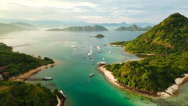 Waecicu Beach Labuan Bajo aerial view with turquoise water, boats, and surrounding green hills